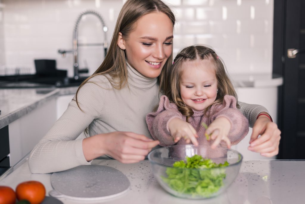 Una donna e una bambina preparano un'insalata insieme, insegnando l'importanza di un'alimentazione sana e equilibrata