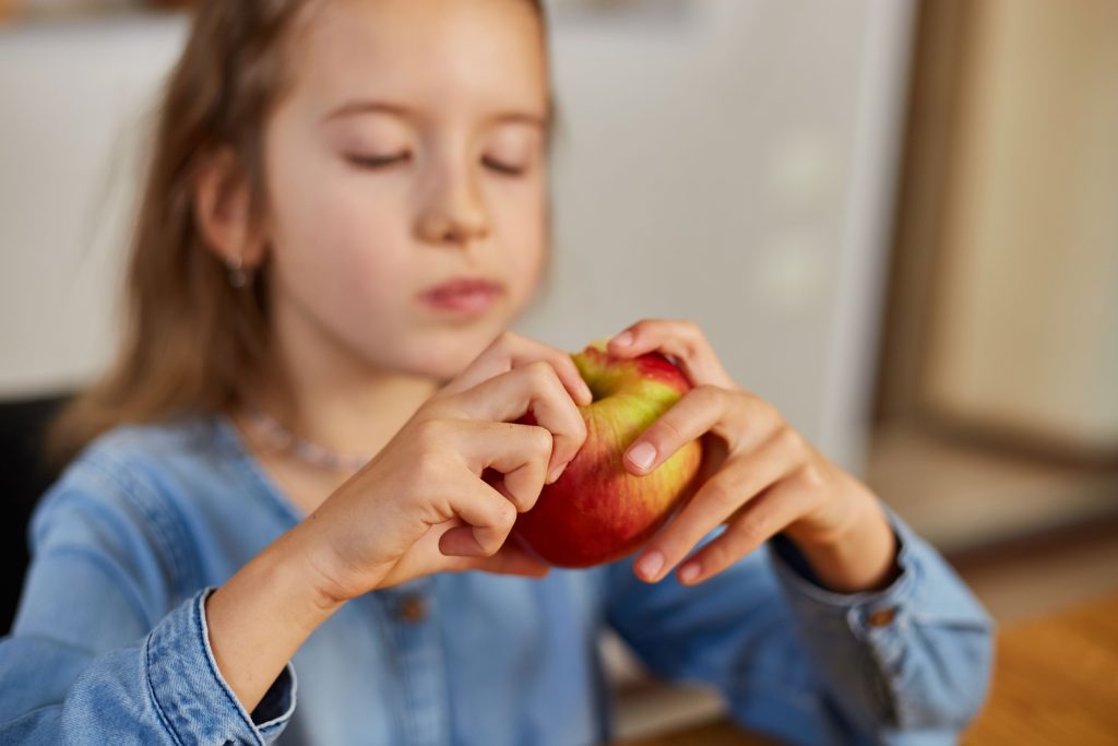 Una bambina gusta una mela, rappresentando l'importanza di una dieta sana e nutriente per i più piccoli